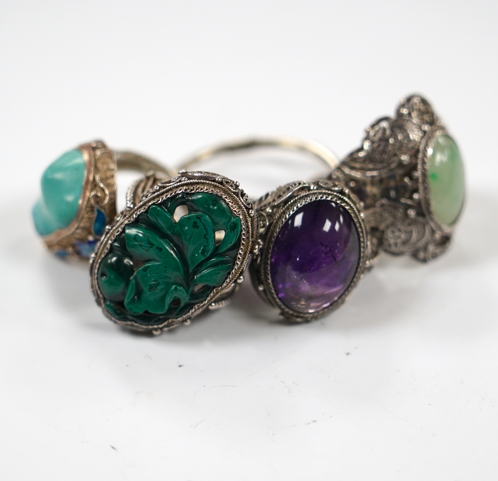 Four assorted Chinese white metal filigree and gem set rings, including turquoise and amethyst.